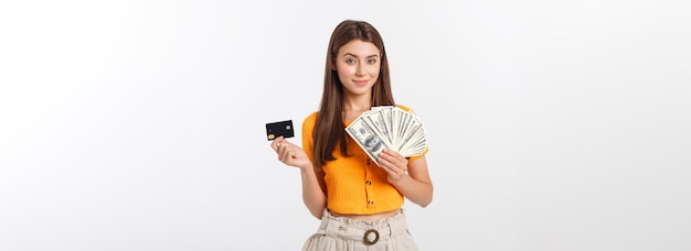 Foto de mujer joven feliz de pie aislado sobre fondo gris mirando a un lado sosteniendo dinero y cr