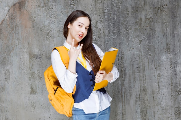 Foto de mujer joven con mochila amarilla con carpeta. foto de alta calidad