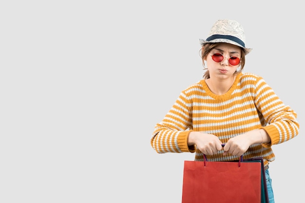 Foto de mujer joven morena con gafas de sol sosteniendo bolsas de la compra. Foto de alta calidad