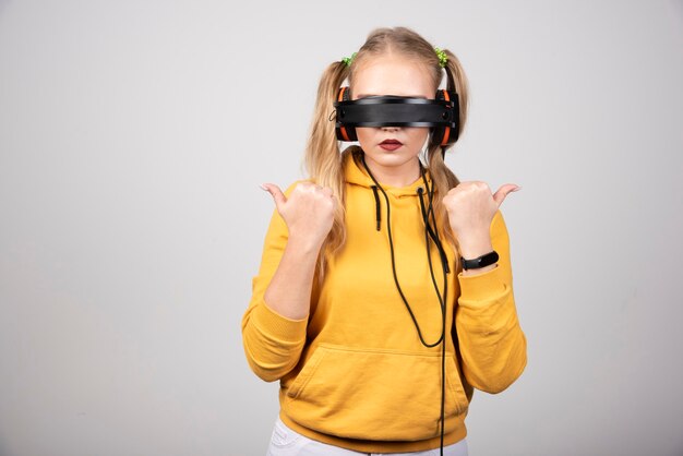 Foto de mujer joven optimista posando y escuchando música con auriculares.