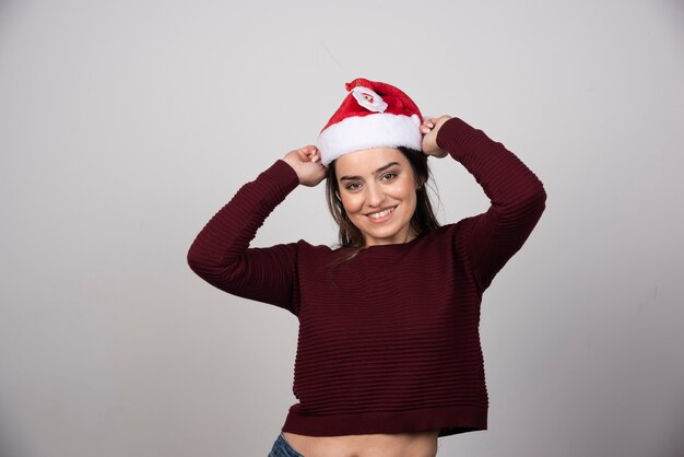Foto de mujer joven con sombrero de Navidad mirando a la cámara.