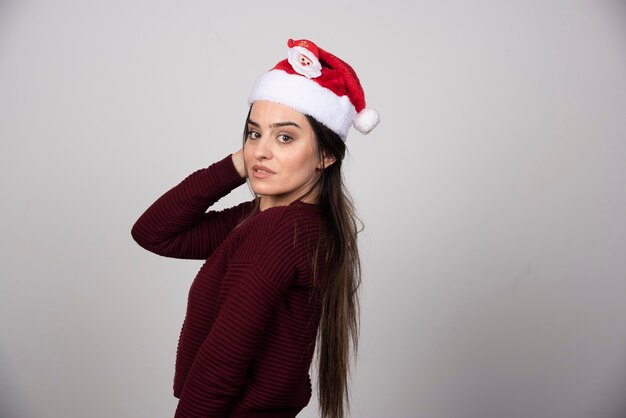 Foto de mujer joven con sombrero de Navidad mirando a la cámara.