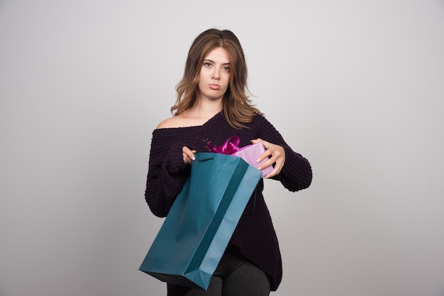 Foto de mujer joven sosteniendo bolsas de la compra.