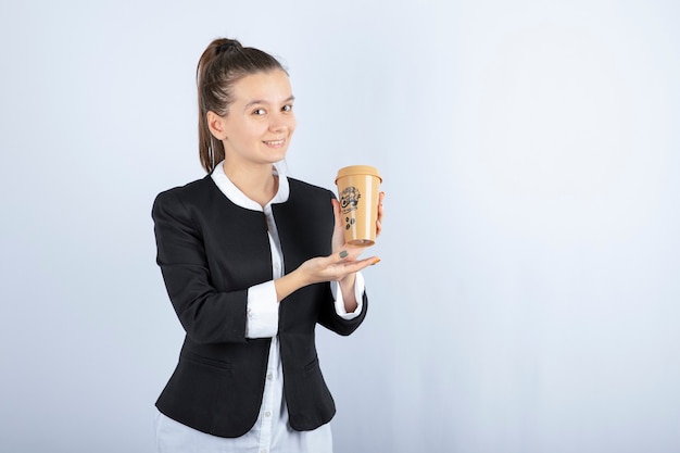 Foto de mujer joven sosteniendo una taza de café en blanco.