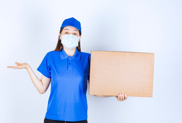 Foto gratuita foto de mujer joven en uniforme y máscara médica con caja de papel.