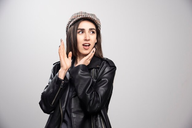 Foto de una mujer mirando a otro lado con gorra y chaqueta de cuero negro.