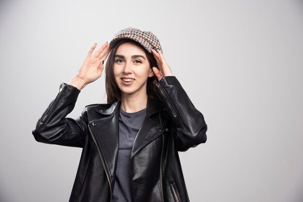 Foto de una mujer posando con gorra y chaqueta de cuero negro.