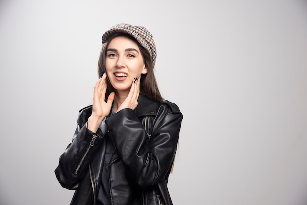 Foto de una mujer posando con gorra y chaqueta de cuero negro.