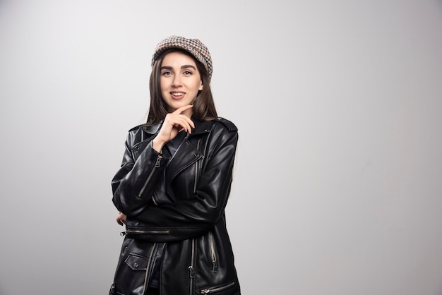 Foto de una mujer posando con gorra y chaqueta de cuero negro.