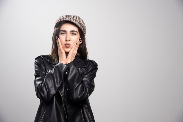 Foto de una mujer posando con gorra y chaqueta de cuero negro.