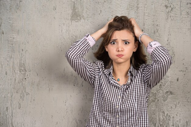 Foto gratuita foto de mujer preocupada en camisa a cuadros sosteniendo su cabeza