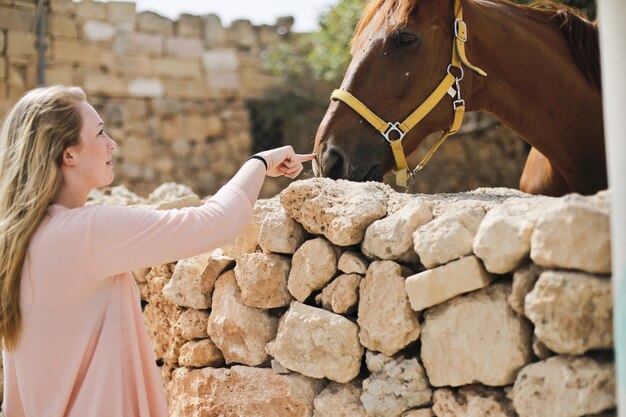 Foto de una mujer rubia y un caballo marrón