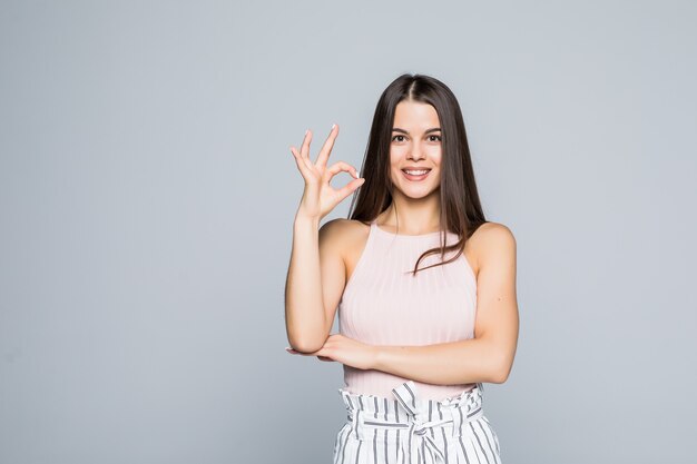 Foto de mujer sonriente bastante joven que se encuentran aisladas sobre la pared blanca.