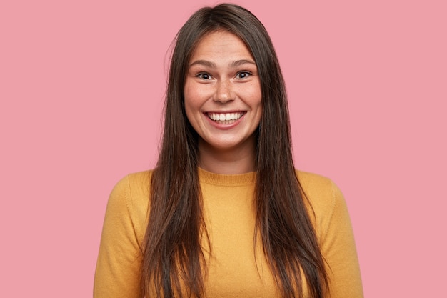 Foto de mujer sonriente con cabello oscuro, de buen humor, se regocija en la promoción en el trabajo