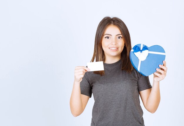 Foto de mujer sonriente joven sosteniendo una caja de regalo en forma de corazón.