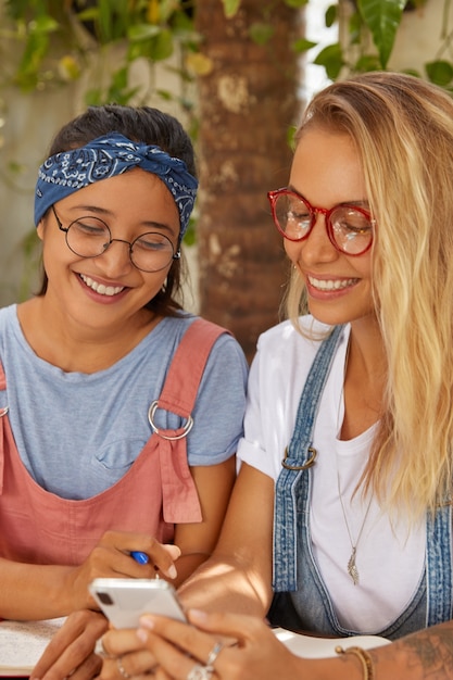 Foto de mujeres alegres de raza mixta miran con expresiones alegres