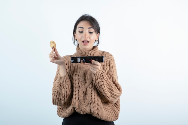 Foto de niña comiendo galletas de chip sobre fondo blanco.