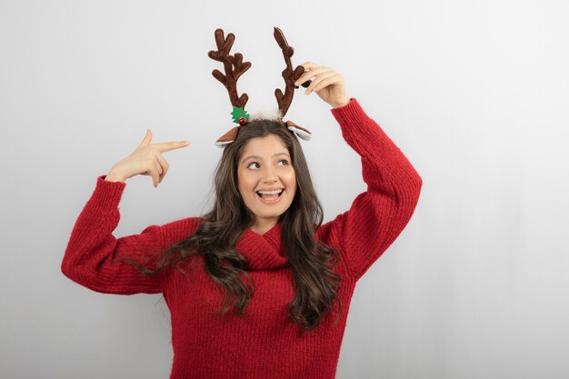 Foto de niña positiva señalar con el dedo a la venda de ciervo Navidad.