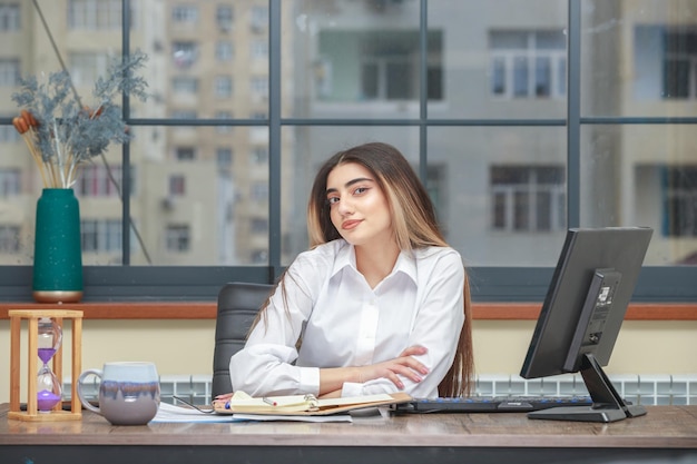 Foto de una niña sentada en el escritorio y sonriendo a la cámara.