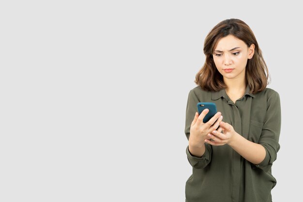 Foto de niña con teléfono celular de pie y revisando sus mensajes