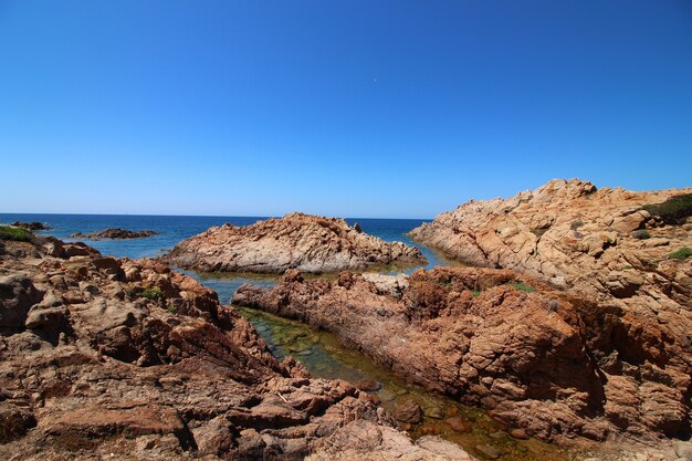 Foto de paisaje de la orilla del mar con grandes rocas en un cielo azul claro