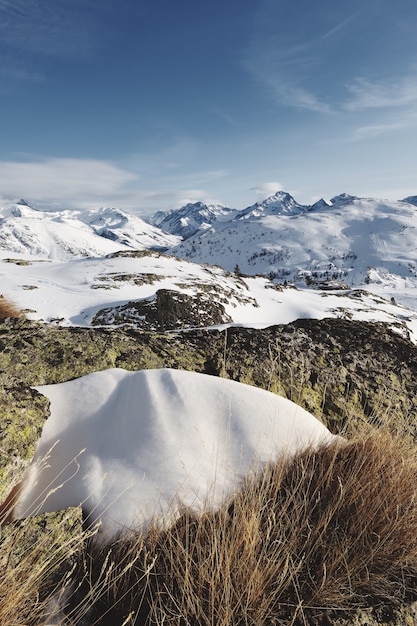Foto panorámica de los Alpes franceses cubiertos de nieve con el sol brillando bajo un cielo azul
