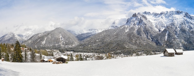 Foto panorámica de hermosas montañas cubiertas de nieve y cabañas