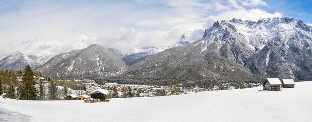 Foto panorámica de hermosas montañas cubiertas de nieve y cabañas