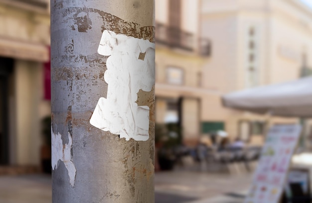 Foto gratuita foto de una pegatina blanca rota en un poste callejero