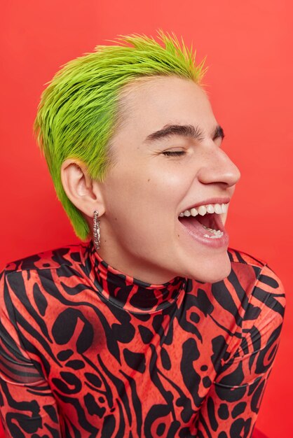 Foto de perfil de chica hipster despreocupada se ríe alegremente se divierte el peinado verde de moda se siente muy feliz apariencia exótica aislada sobre pared roja