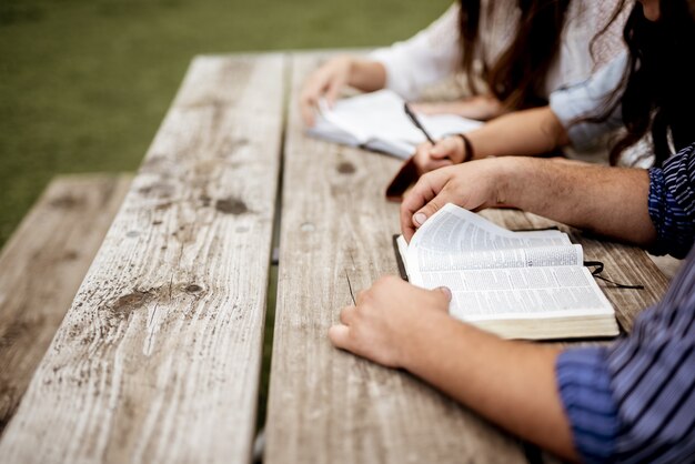 Foto de personas sentadas cerca unas de otras y leyendo la Biblia.