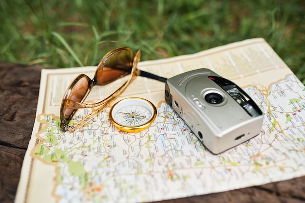 Foto de primer plano de la brújula en el mapa junto a la cámara y las gafas de sol