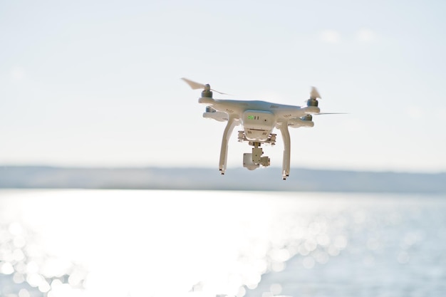 Foto de primer plano de un dron volando sobre el lago y tomándole fotos