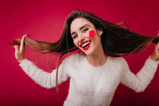 Foto de primer plano de encantadora niña caucásica jugando con su pelo largo