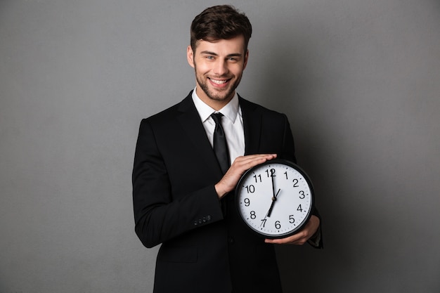 Foto de primer plano de hombre guapo sonriente en traje negro con reloj