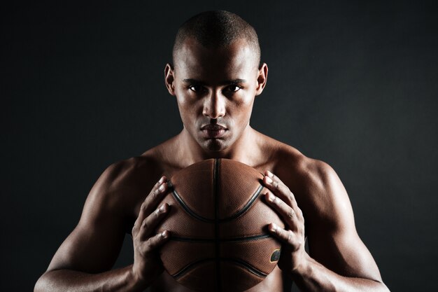 Foto de primer plano del jugador de baloncesto afroamericano sosteniendo la pelota con las dos manos