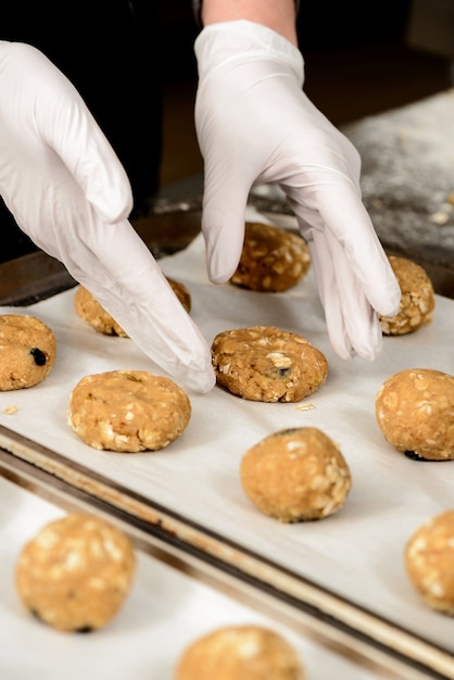 Foto gratuita foto de primer plano de manos poniendo sabrosas galletas en una bandeja para hornear