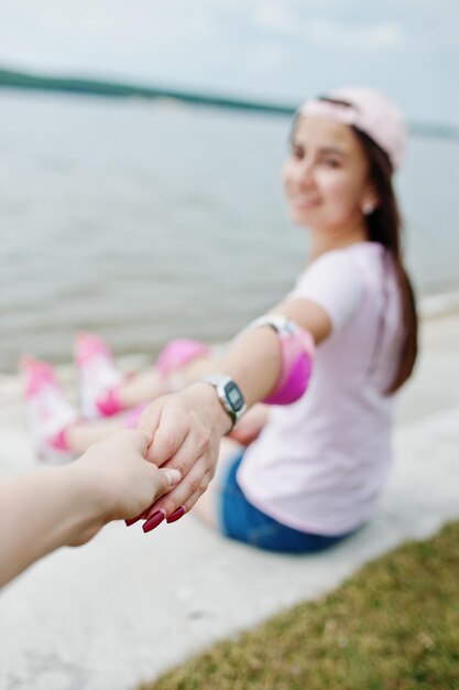 Foto de primer plano de una pareja tomándose de la mano mientras se sienta en el suelo junto al lago