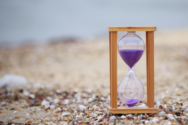 Foto de primer plano de un reloj de arena de madera en la playa Foto de alta calidad