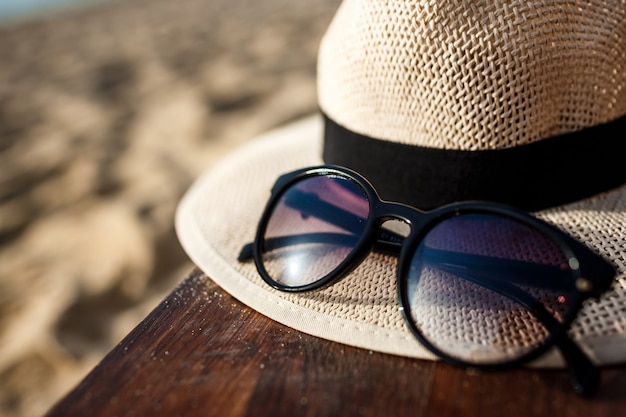 Foto de primer plano de sombrero y gafas en la playa