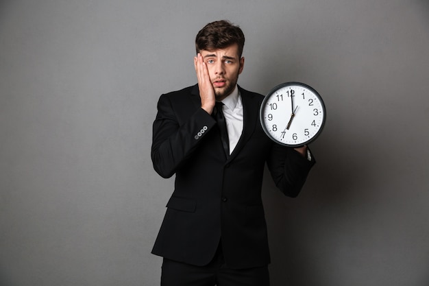 Foto de primer plano del trabajador molesto en traje con reloj,