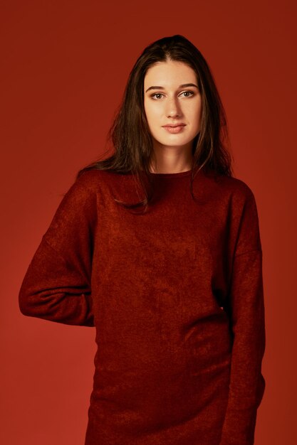 Foto profesional de una linda joven morena con un bonito vestido boho rojo de verano, posando en un estudio con fondo rojo. Foto de moda primavera verano