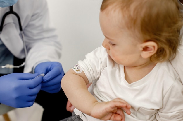 Foto recortada del hombro de un niño con vacunación con curitas