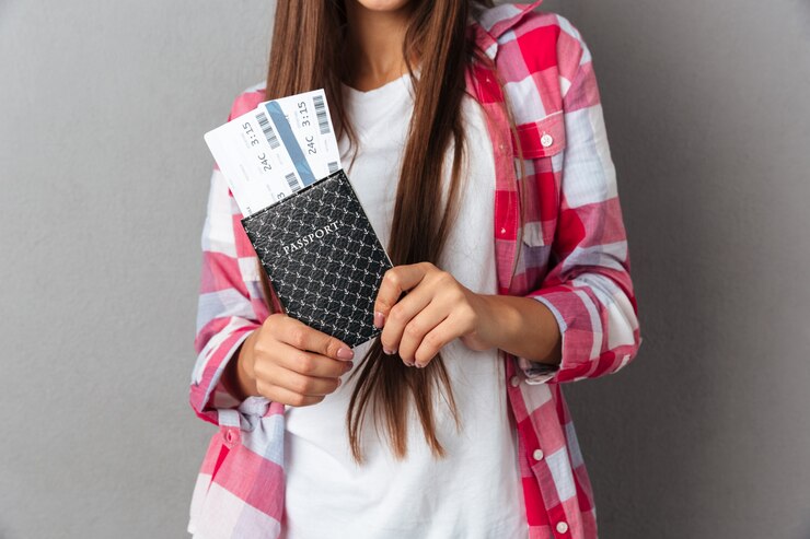 Foto recortada de mujer joven con pasaporte con boletos de avión