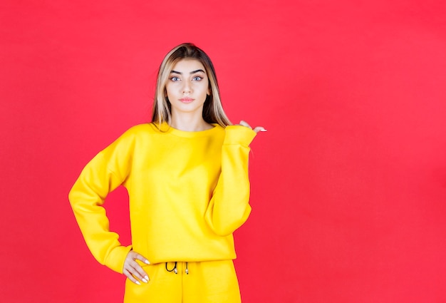 Foto de retrato de una chica seria modelo de pie y apuntando a un lado