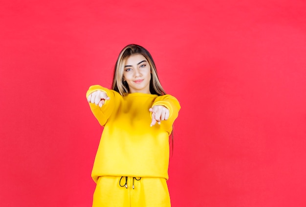 Foto de retrato de una hermosa niña modelo de pie y apuntando a la cámara