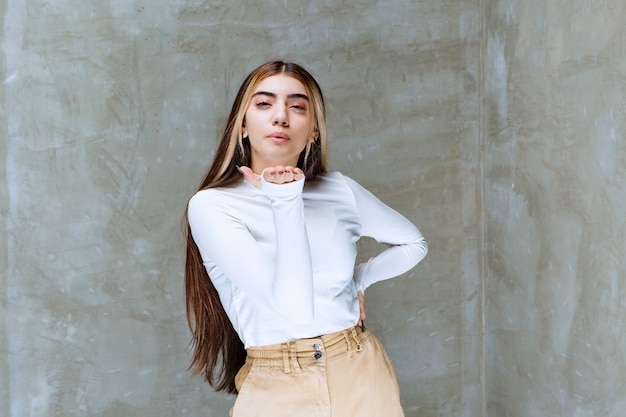 Foto de retrato de una hermosa niña modelo de pie y soplando un beso al aire