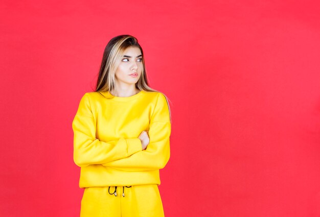 Foto de retrato de un modelo de niña seria de pie y posando con los brazos cruzados