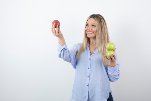 Foto de retrato de una mujer bastante atractiva modelo de pie y sosteniendo manzanas frescas.