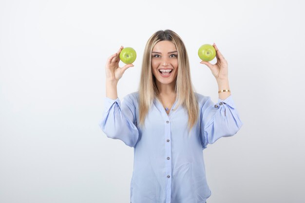 Foto de retrato de una mujer bastante atractiva modelo de pie y sosteniendo manzanas frescas.